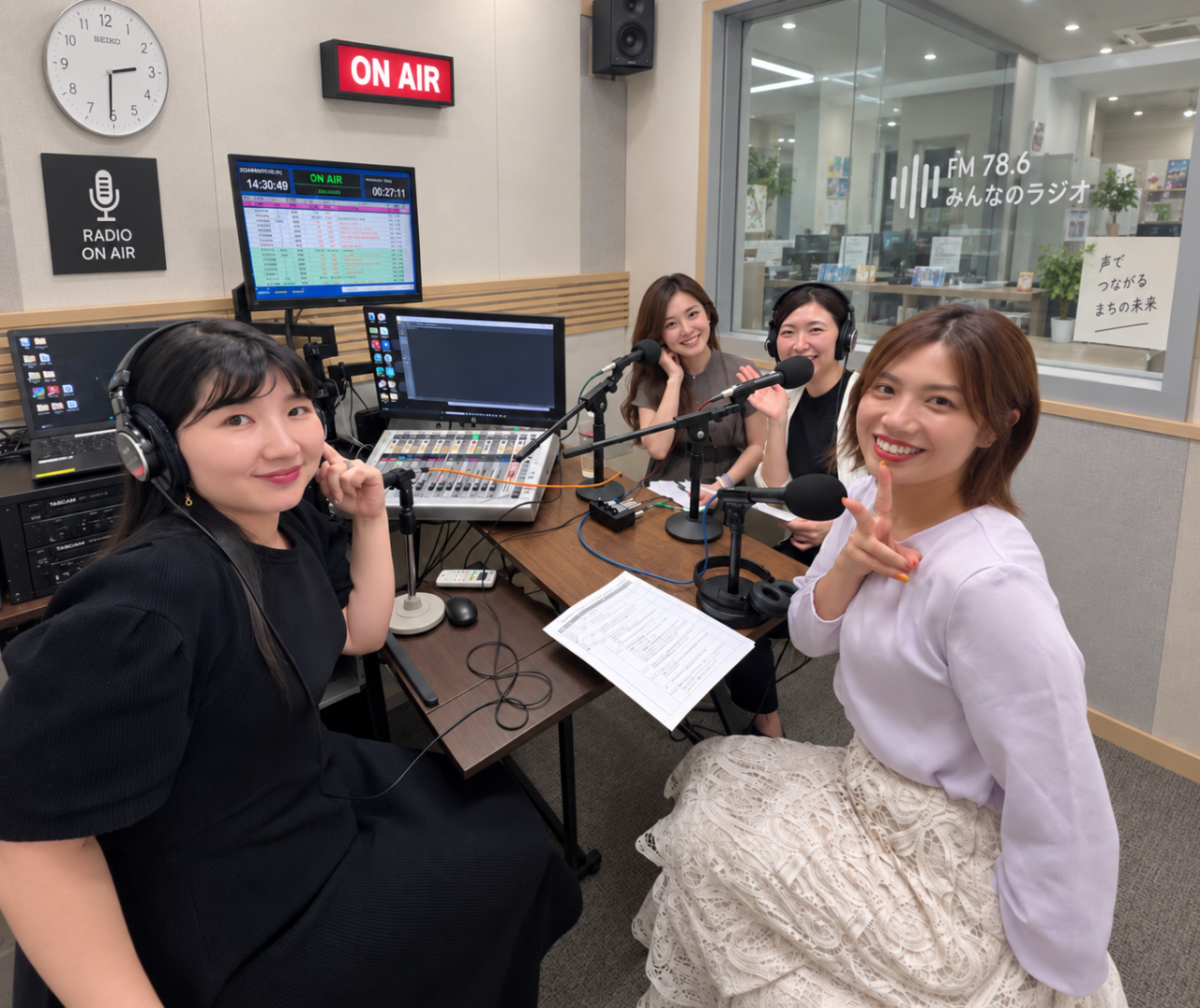 ラジオスタジオでマイクを囲む4人の出演者